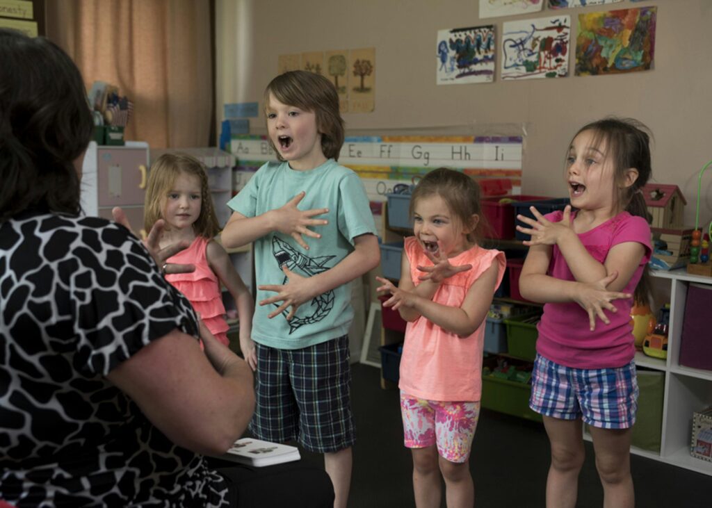 four siblings learning new words with their mom. in their play room with kids drawings on the wall and alphabets.