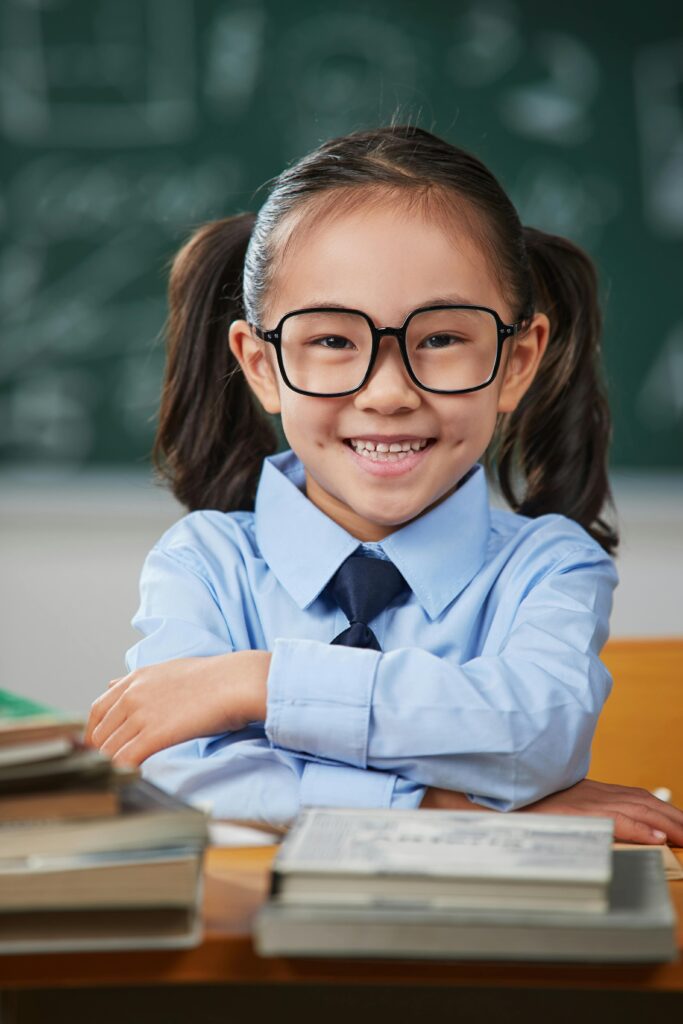A smiling student girl looking at the camera, holding a notebook and pen, with a bright and confident expression, showcasing positivity and engagement in learning.