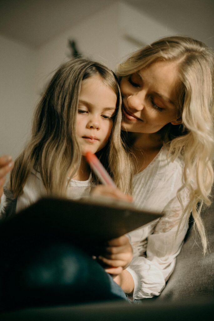 A parent gently encouraging their child while they work on homework together at a table, with books and a laptop, showcasing a supportive and motivating learning moment.